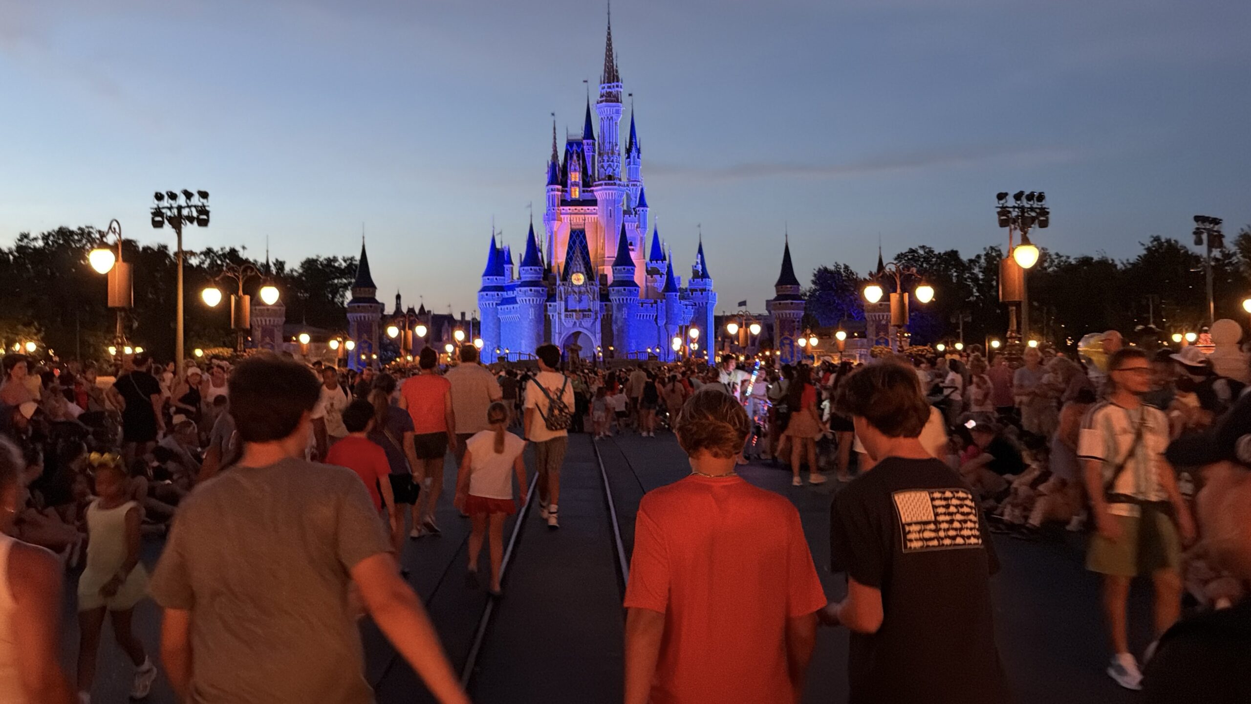 Guests walking toward Cinderella Castle during a summer evening at Walt Disney World.
